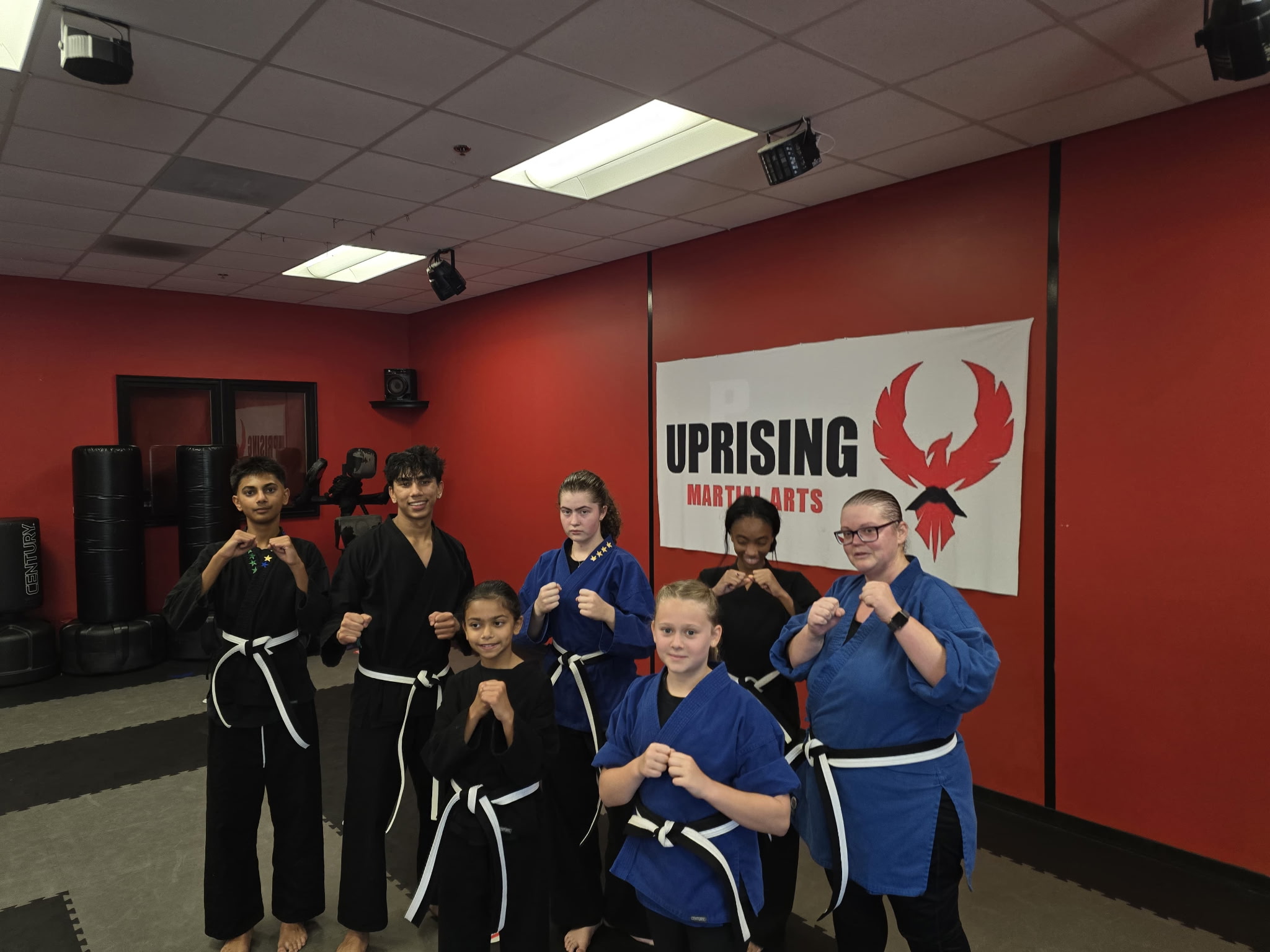 A group of Uprising students wearing white belts together in the studio