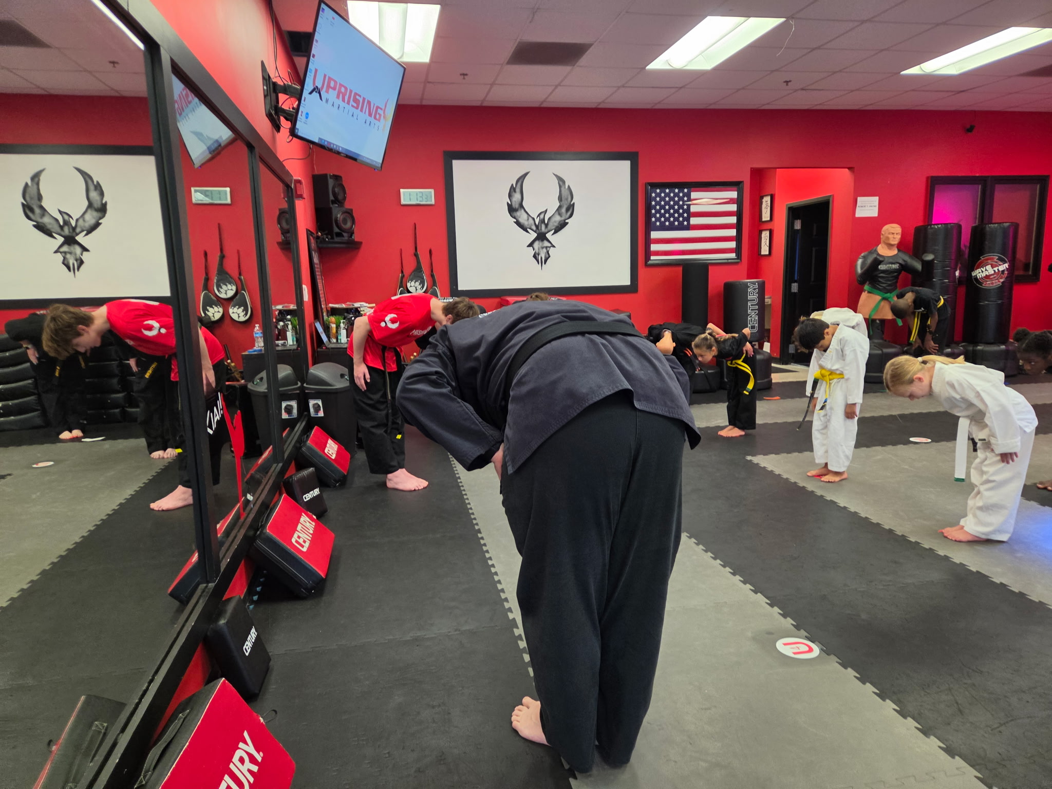 Young students and their instructors bowing together in class