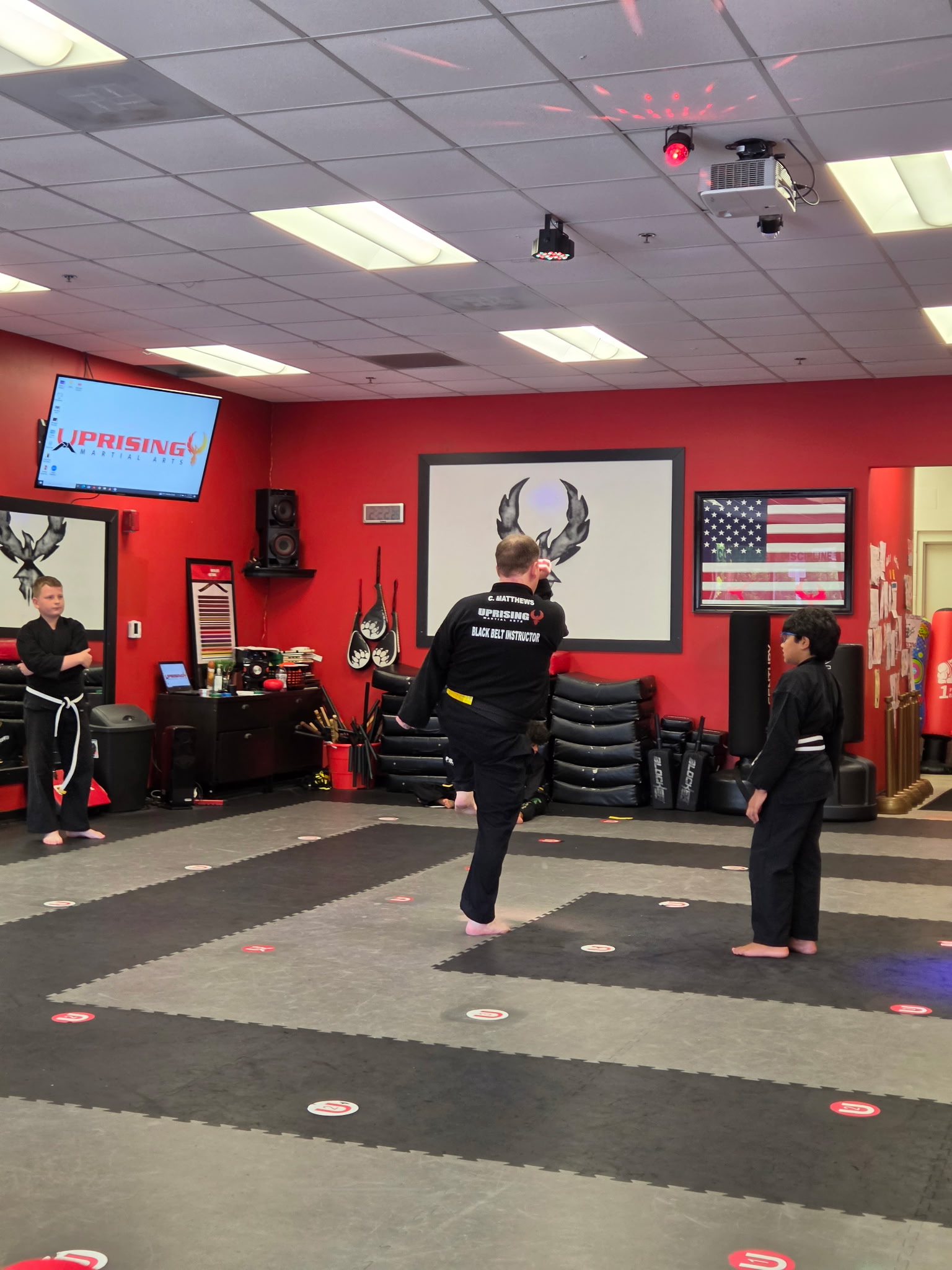An Uprising black belt instructor demonstrating a movement while younger students watch